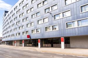 a large gray building with red signs on it at Leonardo Hotel Vienna Schönbrunn in Vienna