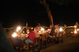 a group of people sitting at a table at night at Selous River Camp in Kwangwazi