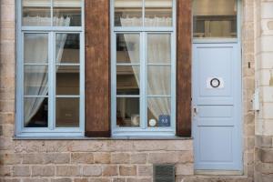 eine weiße Tür und Fenster auf einem Backsteingebäude in der Unterkunft Chambre d'Hôtes Les Clés des Places in Arras