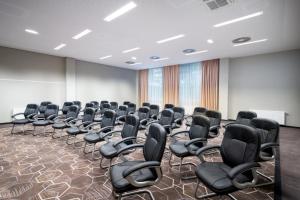 una habitación vacía con sillas negras en una habitación en Leonardo Hotel Vienna Schönbrunn en Viena