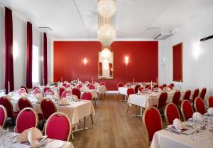 uma sala de jantar com mesas e cadeiras e paredes vermelhas em Hotel Ringkøbing em Ringkøbing