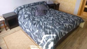 a bed with a black comforter in a room at Pid lisochkom in Verkhovyna