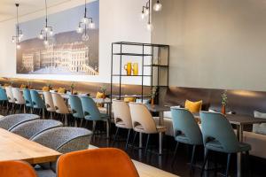 una fila de mesas y sillas en un restaurante en Leonardo Hotel Vienna Schönbrunn, en Viena