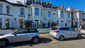 two cars parked in a parking lot in front of a house at Willows Guest House in Great Yarmouth