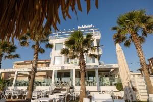 a hotel with palm trees in front of it at Baldinini Hotel in Rimini