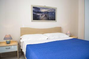 een slaapkamer met een bed met een blauwe deken bij Appartamenti in Via Schipa Pescoluse in Marina di Pescoluse