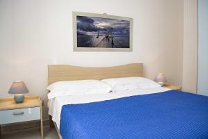 マリーナ・ディ・ペスコルーゼにあるAppartamenti in Via Schipa Pescoluseのベッドルーム1室(青い毛布付きのベッド1台付)