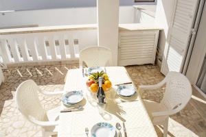 un tavolo bianco con sedie bianche e frutta di Appartamenti in Via Schipa Pescoluse a Marina di Pescoluse