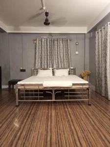 een groot bed in een kamer met een houten vloer bij Ellys home stay in Guwahati