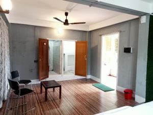 een woonkamer met een plafondventilator en een tafel en stoelen bij Ellys home stay in Guwahati