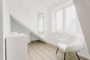a white chair in a white room with a window at Küsten Suite de See - Suite 2 direkte Deichlage, Balkon, 77qm in Greetsiel