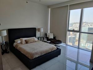 sypialnia z łóżkiem, krzesłem i oknami w obiekcie Penthouse liu east piso 35 valle oriente w mieście Monterrey