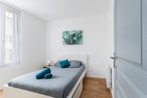 biała sypialnia z łóżkiem z niebieskimi poduszkami w obiekcie Le Musée 1, Cosy 2 pièces w mieście Bergerac