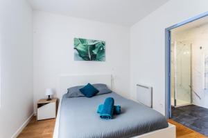 sypialnia z łóżkiem z niebieskimi poduszkami w obiekcie Le Musée 1, Cosy 2 pièces w mieście Bergerac