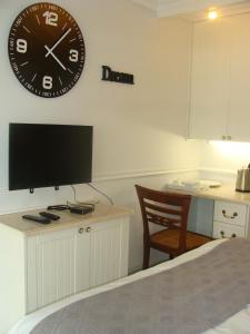 a bedroom with a clock on the wall and a desk with a chair at Lonehill - Suite 1 in Sandton