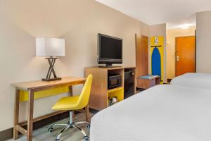 Habitación de hotel con cama, escritorio y TV. en Days Inn & Suites by Wyndham Rocky Mount Golden East, en Rocky Mount