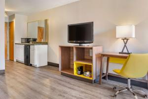 Habitación con TV, escritorio y silla. en Days Inn & Suites by Wyndham Rocky Mount Golden East, en Rocky Mount