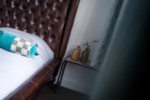 een bed met een leren hoofdeinde en twee vazen op een tafel bij Hotel Centraal in Someren