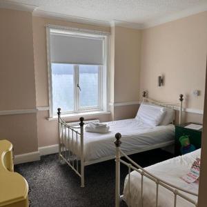 1 dormitorio con 2 camas y ventana en Hatters Hotel, en Skegness