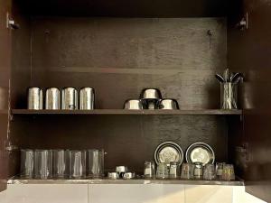 a shelf filled with glasses and pots and pans at 2 Bhk apt near Manipal hospital by RDBL Hospitality Private limited in New Delhi