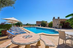 a pool with chairs and a table and an umbrella at Finca Tanca in Calonge