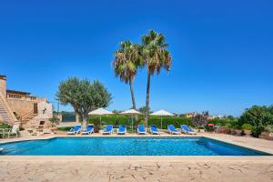 a swimming pool with lounge chairs and palm trees at Finca Tanca in Calonge