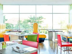 ein Restaurant mit Tischen, Stühlen und Fenstern in der Unterkunft Hotel Ibis Semarang Simpang Lima in Semarang