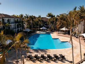 a large swimming pool with chairs and palm trees at Mercure Gold Coast Resort in Gold Coast