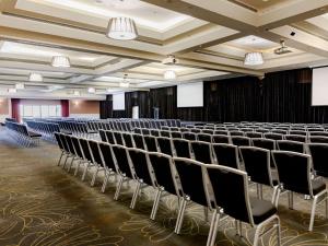 Mercure Gold Coast Resort في غولد كوست: قاعة محاضرات فارغة مع صفوف من الكراسي