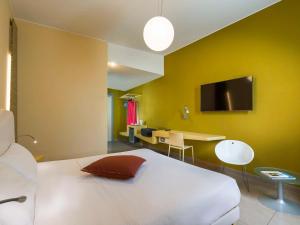 a bedroom with a bed and a desk and a tv at ibis Styles Catania Acireale in Acireale