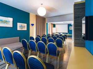 une salle de conférence avec des chaises bleues et un panneau blanc dans l'établissement ibis Styles Catania Acireale, à Acireale