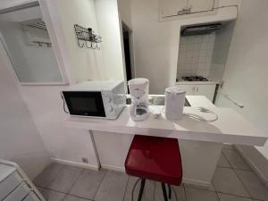 a white counter with a microwave and a red chair at Appartements Brussel in Brussels