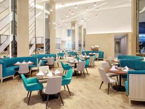 a dining room with blue chairs and tables at Novotel Samator Surabaya Timur in Surabaya