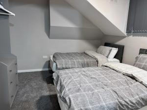 a bedroom with two beds and a staircase at Modernised 3 Bedroom House, Lascelle Residence in Roundhay