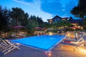 a large swimming pool with chairs and umbrellas at Olea Dei Holiday Apartments in San Felice del Benaco