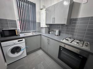 a kitchen with a washing machine and a washer at Modernised 3 Bedroom House, Lascelle Residence in Roundhay