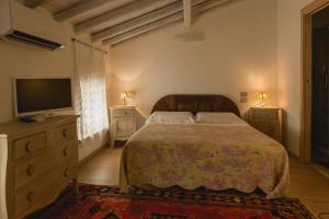 um quarto com uma cama, uma televisão e uma cómoda em La Casetta in Valpolicella em Monte