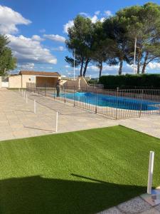 einen Zaun mit grünem Gras neben einem Pool in der Unterkunft Appartement « Séville » à Avignon in Avignon