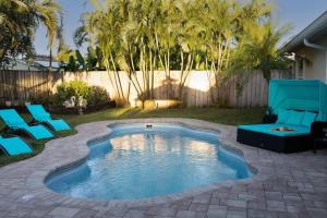 a swimming pool in a yard with blue chairs and trees at Relaxation Villa in Royal Palm Beach