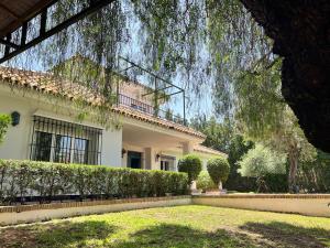 uma grande casa branca com uma árvore em frente em Casa Ciaurriz em Mairena del Aljarafe