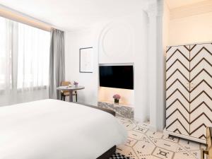 a white bedroom with a bed and a tv at Fairmont La Marina Rabat Sale Hotel And Residences in Rabat