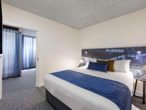 a hotel room with a large bed and a table at Mercure Melbourne St Kilda Road in Melbourne