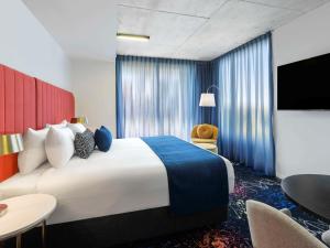 a hotel room with a large bed and a table at Mercure Melbourne St Kilda Road in Melbourne