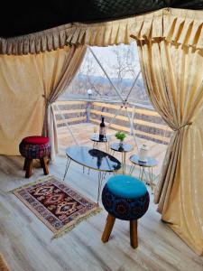Zimmer mit 2 Tischen, 2 Stühlen und einem Fenster in der Unterkunft Berkheva Glamping - ბერხევა გლემპინგი in Zemo Khodasheni