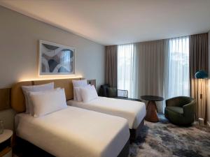 um quarto de hotel com duas camas e uma cadeira em Pullman Sydney Penrith em Penrith