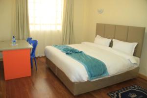 Schlafzimmer mit einem großen Bett, einem Schreibtisch und einem Fenster in der Unterkunft Juniper Green Gardens Resort. in Mweiga