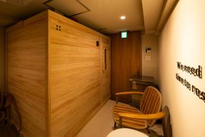 Cette petite chambre est dotée d'un mur en bois et de 2 chaises. dans l'établissement Totonou & GIVE Nakano Sakaue, à Tokyo
