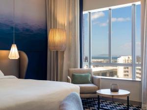 a hotel room with a bed and a chair and a window at Pullman Cape Town City Centre in Cape Town