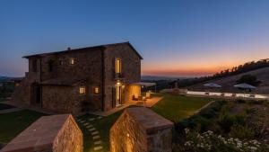 a large stone house with a sunset in the background at CASALE GROTTINI 8, Emma Villas in Manciano