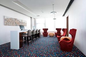 a waiting room with chairs and a table and a bar at Aloft Dalian in Dalian